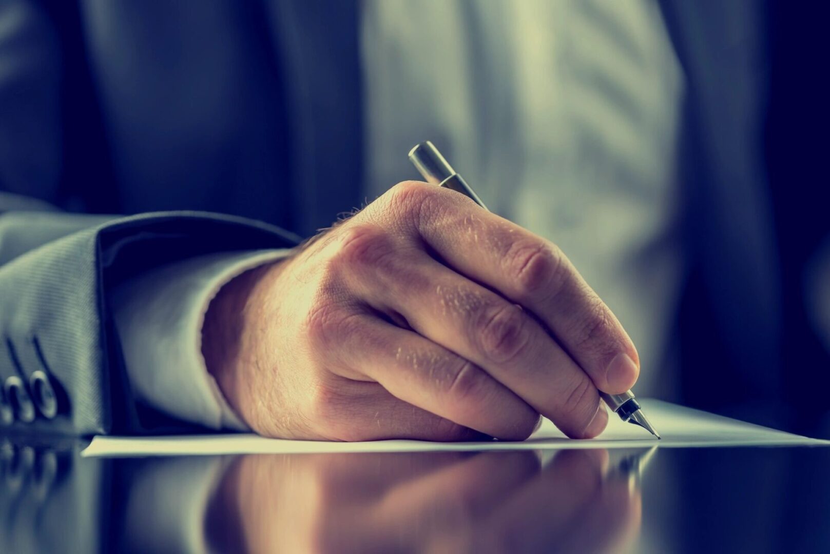 Man signing document with pen.