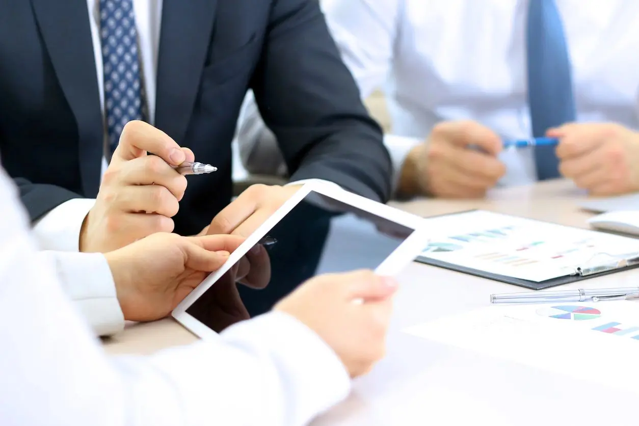 Businesspeople reviewing data on tablet.