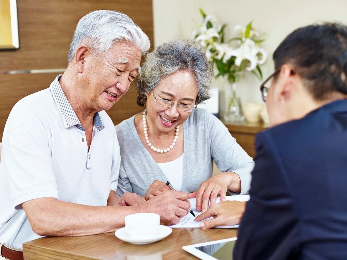 Senior couple signing document with agent.