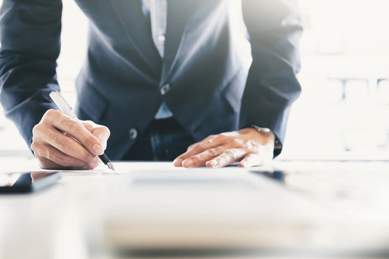 Businessman signing document with pen.