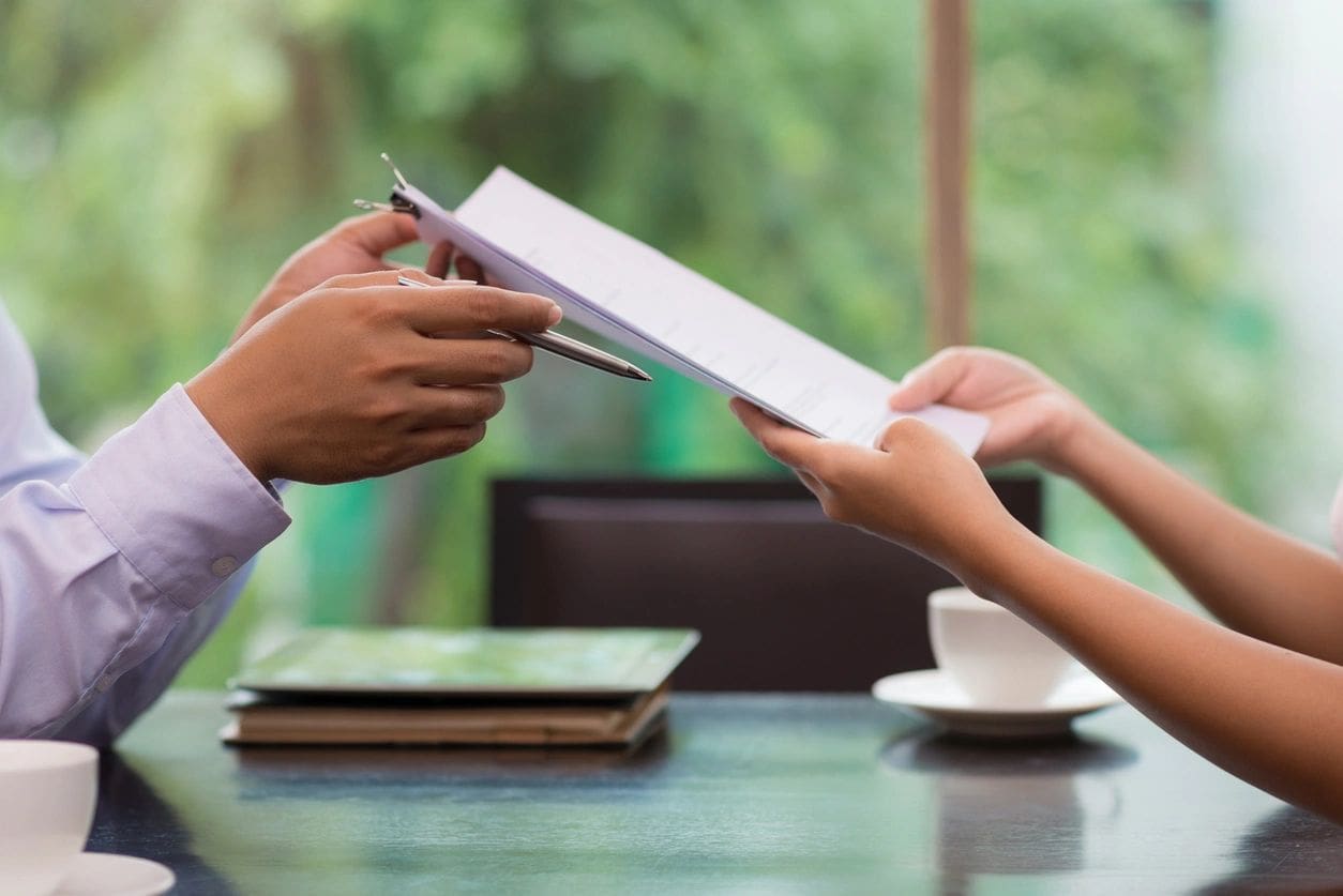 Two hands signing a document with a pen.