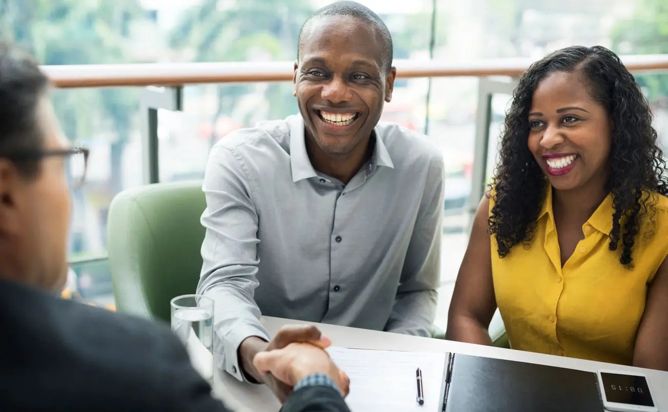 Smiling couple shaking hands during a meeting.