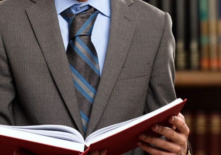 Man in suit holding a red book.